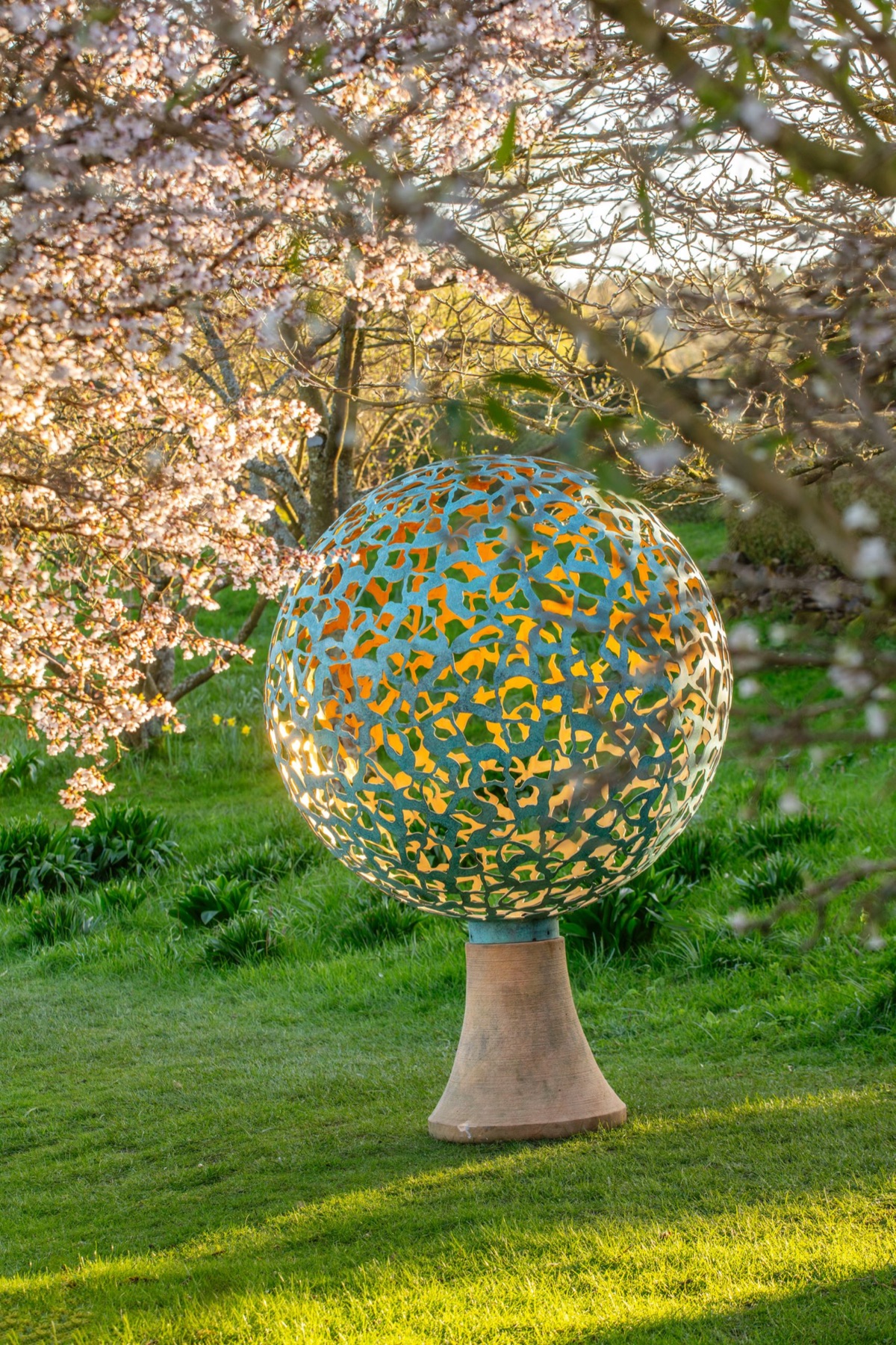A pierced sphere by David Harber under cherry blossom