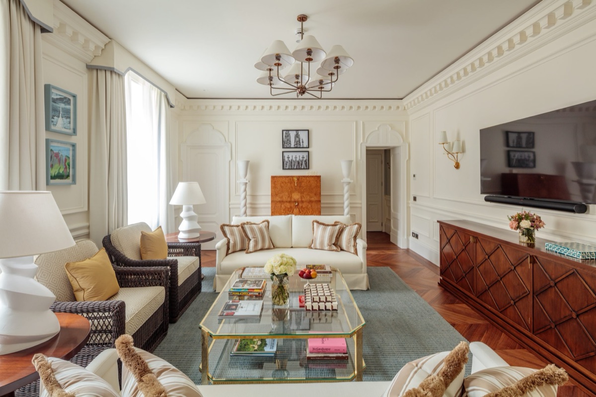 A panelled suite with a chandelier, a burr-walnut cabinet and a herringbone floor