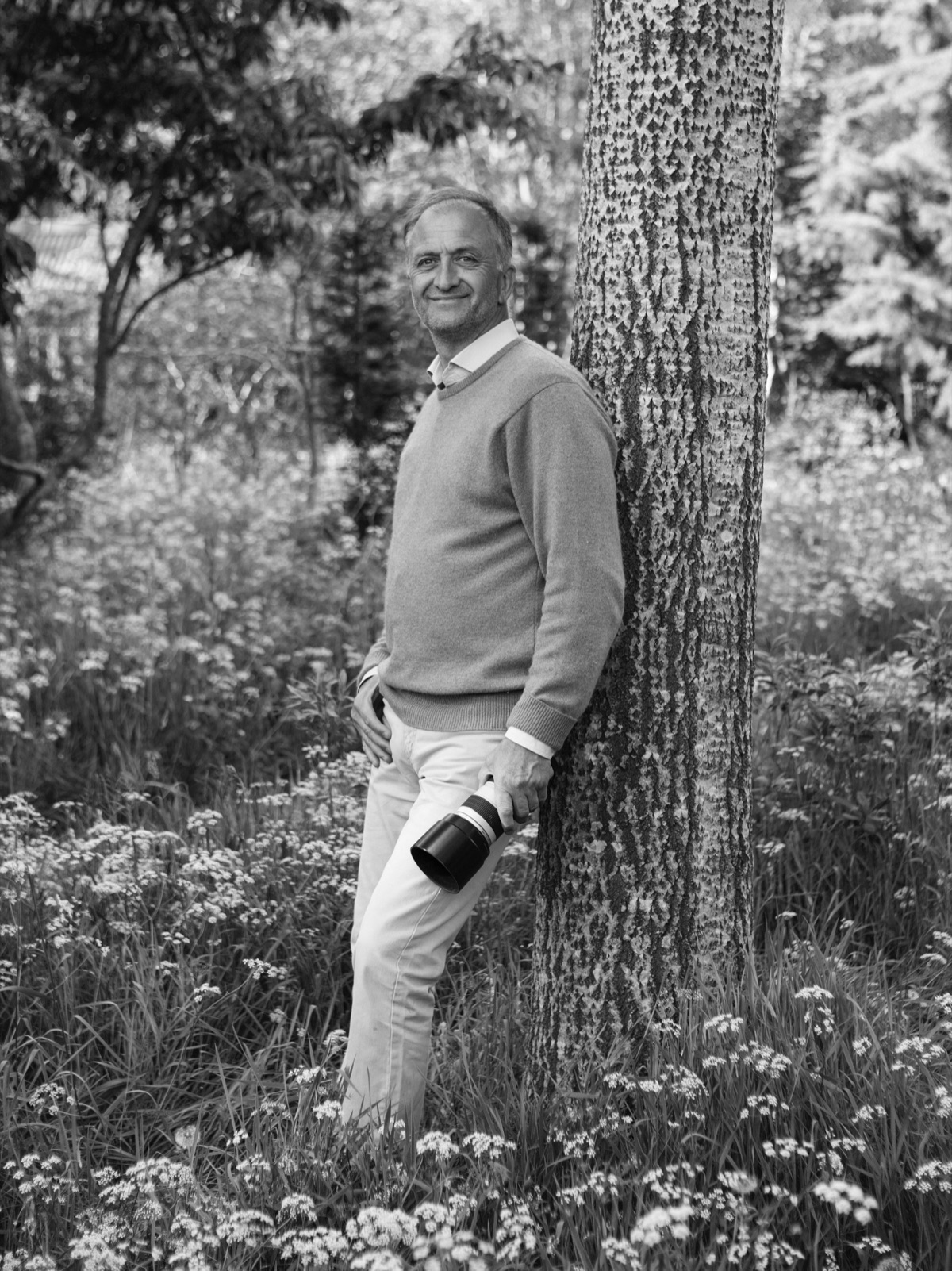 Clive Nichols leaning against a birch tree with his camera